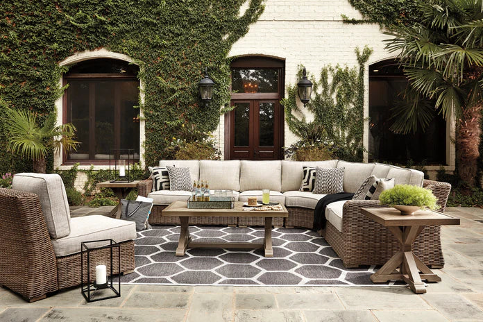 Cozy outdoor patio with Ashley Furniture, featuring a sectional sofa, accent chairs, and dining table in a lush garden setting.