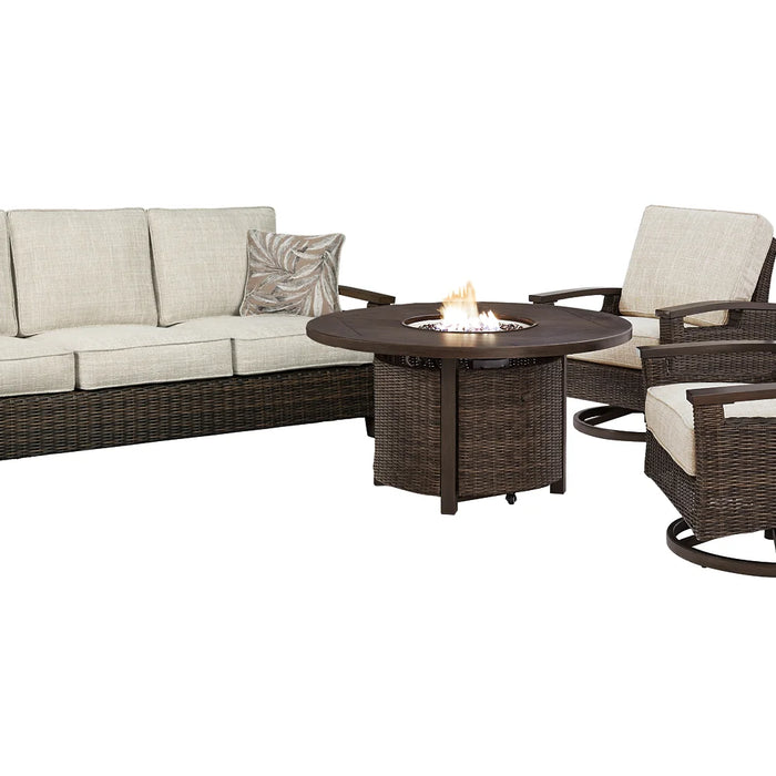 A cozy outdoor scene with a stylish propane fire pit surrounded by a sectional sofa and accent chairs, adorned with colorful pillows, set in a lush, warmly lit backyard.