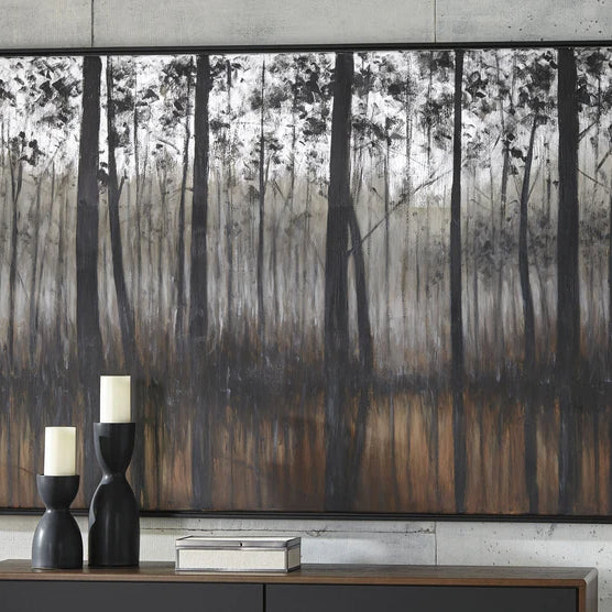 A close up of living room wall with tree wall art above a console table accented with stylish black modern candle holders .